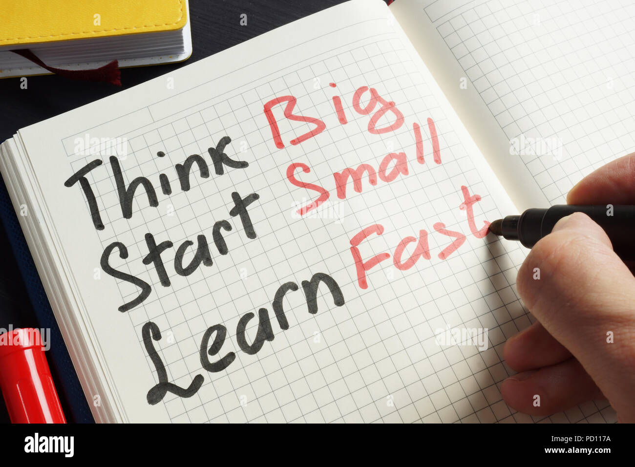 Man is writing Think big, start small, learn fast. Stock Photo