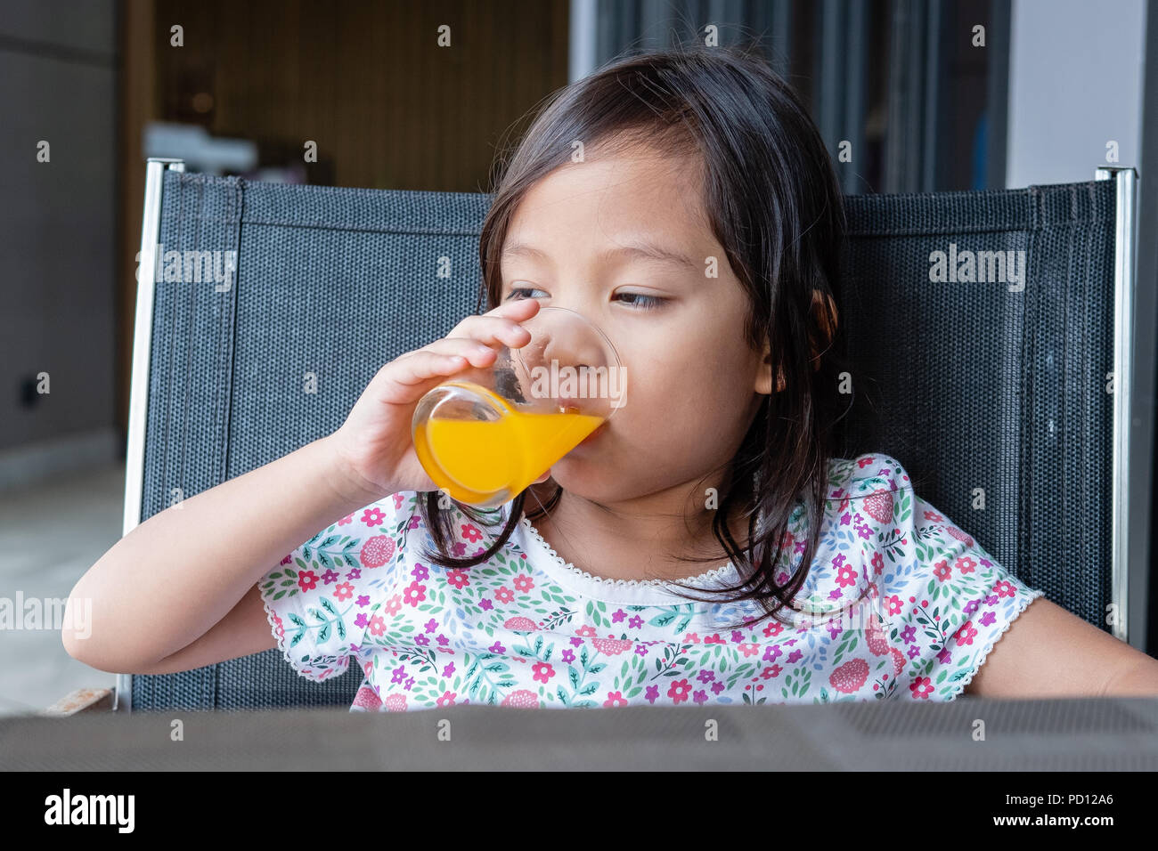 sitting cute little girl drinking orange juice Stock Photo - Alamy