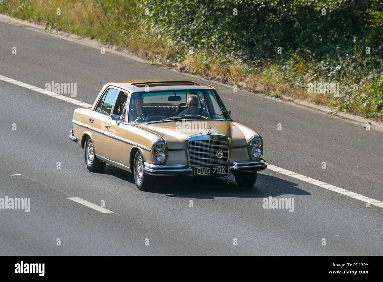 1972 gold Mercedes 280 SE UK Vehicular traffic, transport, collectible vehicles saloon cars, on the 3 lane M55 motorway highway, Blackpool, UK Stock Photo