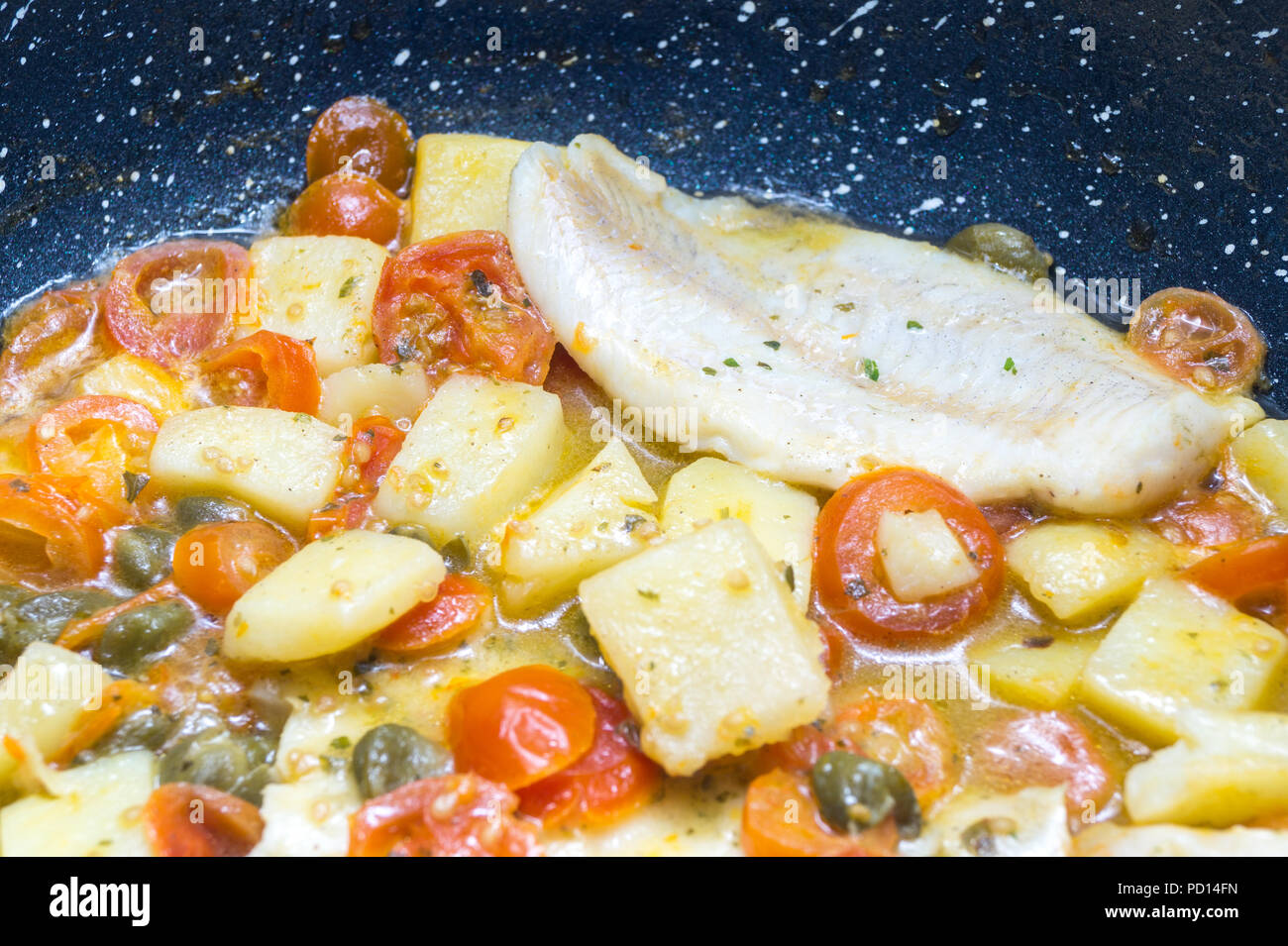 cod cooked in a pan, with tomato, potatoes and capers Stock Photo