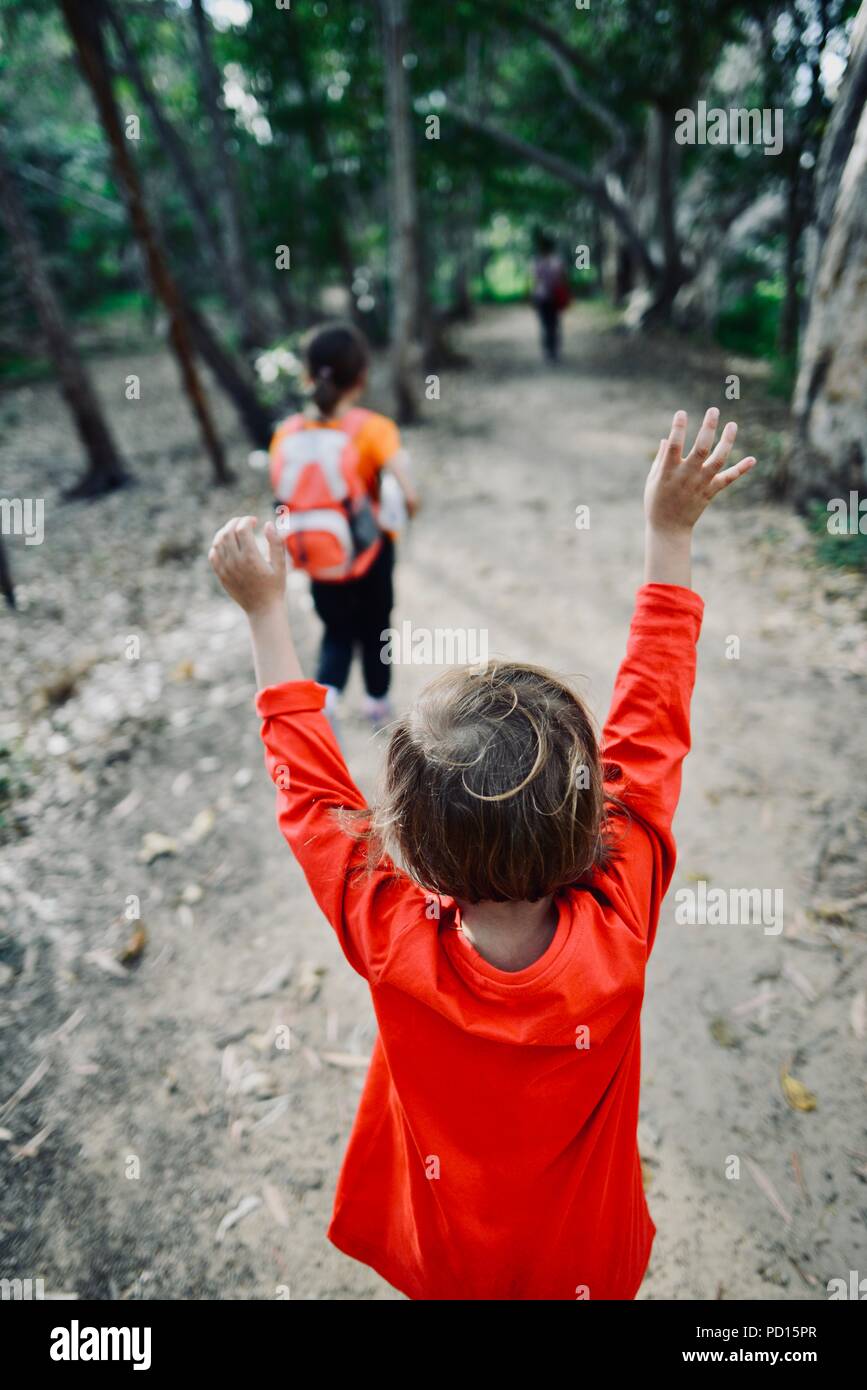 Young girl throws up hands in the air while walking hires stock