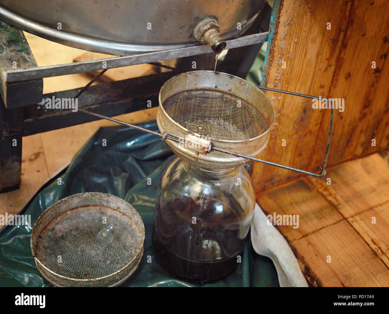 Honey leaking from a honey extractor into a jar, filtered image Stock