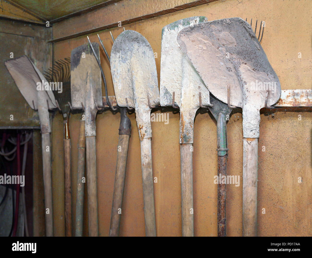 Dirty used shovels hanging on a metal wall in the garage Stock Photo Alamy