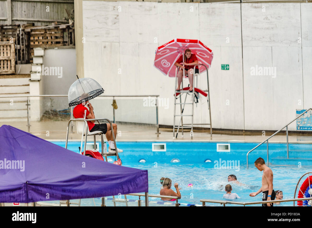 sunbathers and swimmers take refuge as the long dry spell is broken with a heavy downpour at Saltdean Lido, East Sussex. Stock Photo