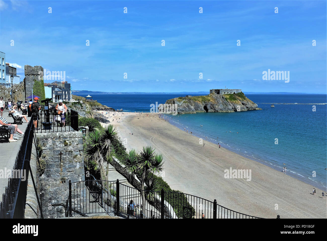 Tenby, Pembrokeshire, South Wales, UK. July 25, 2018.   Holidaymakers enjoying the views from the Esplanade of St, Catherine Island and the South . Stock Photo