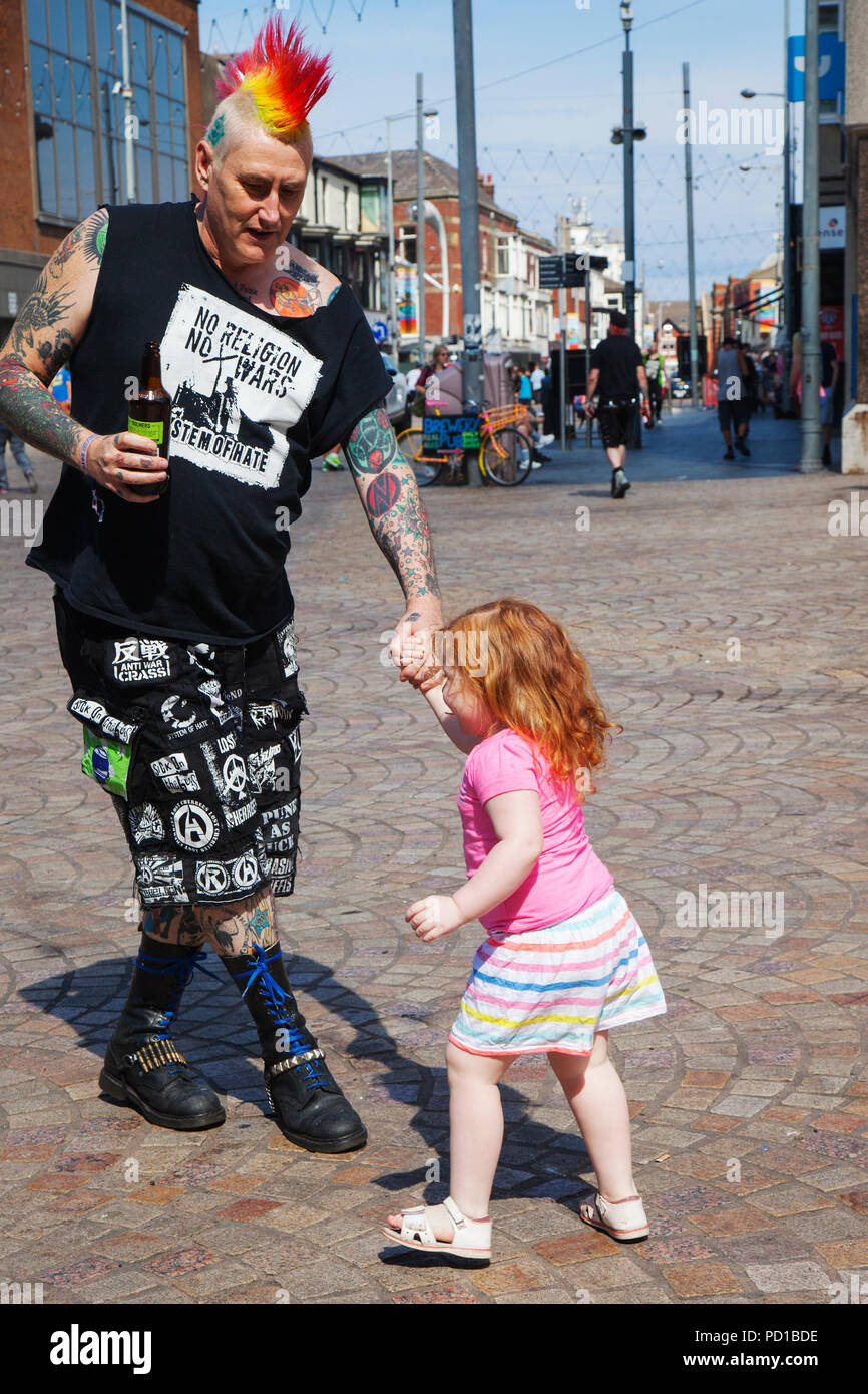Grandad Steve 'No Religion No Wars' with grand daughter Robyn, colourful characters at the resort Rebellion Punk Festival. Rebellion Festival, formerly Holidays in the Sun and the Wasted Festival is a British punk rock festival first held in 1996. Blackpool's annual display of coloured hair, tartan clothing and ripped leg-wear is back as every August in Blackpool, the very best in Punk gather for the social event of the year. Stock Photo