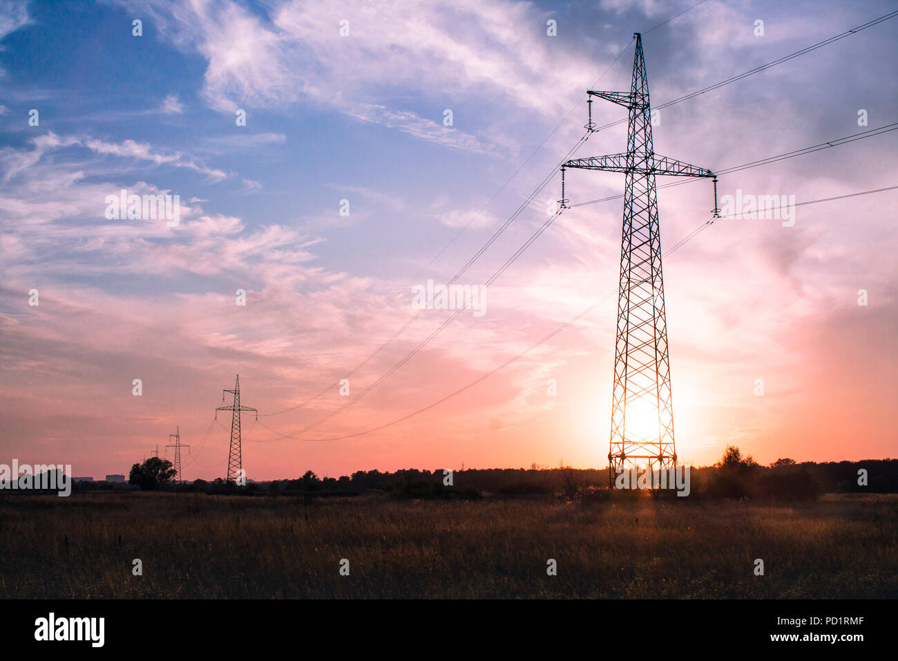 Electricity transmission towers line on beautiful soft colors sunset or sunrise background No people Stock Photo