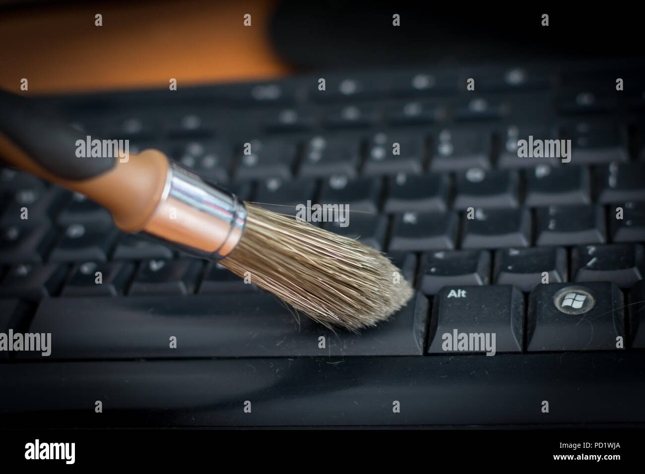 Cleaning keyboard from dust by black&brown brush. Cleaning concept. Office cleaning. Stock Photo