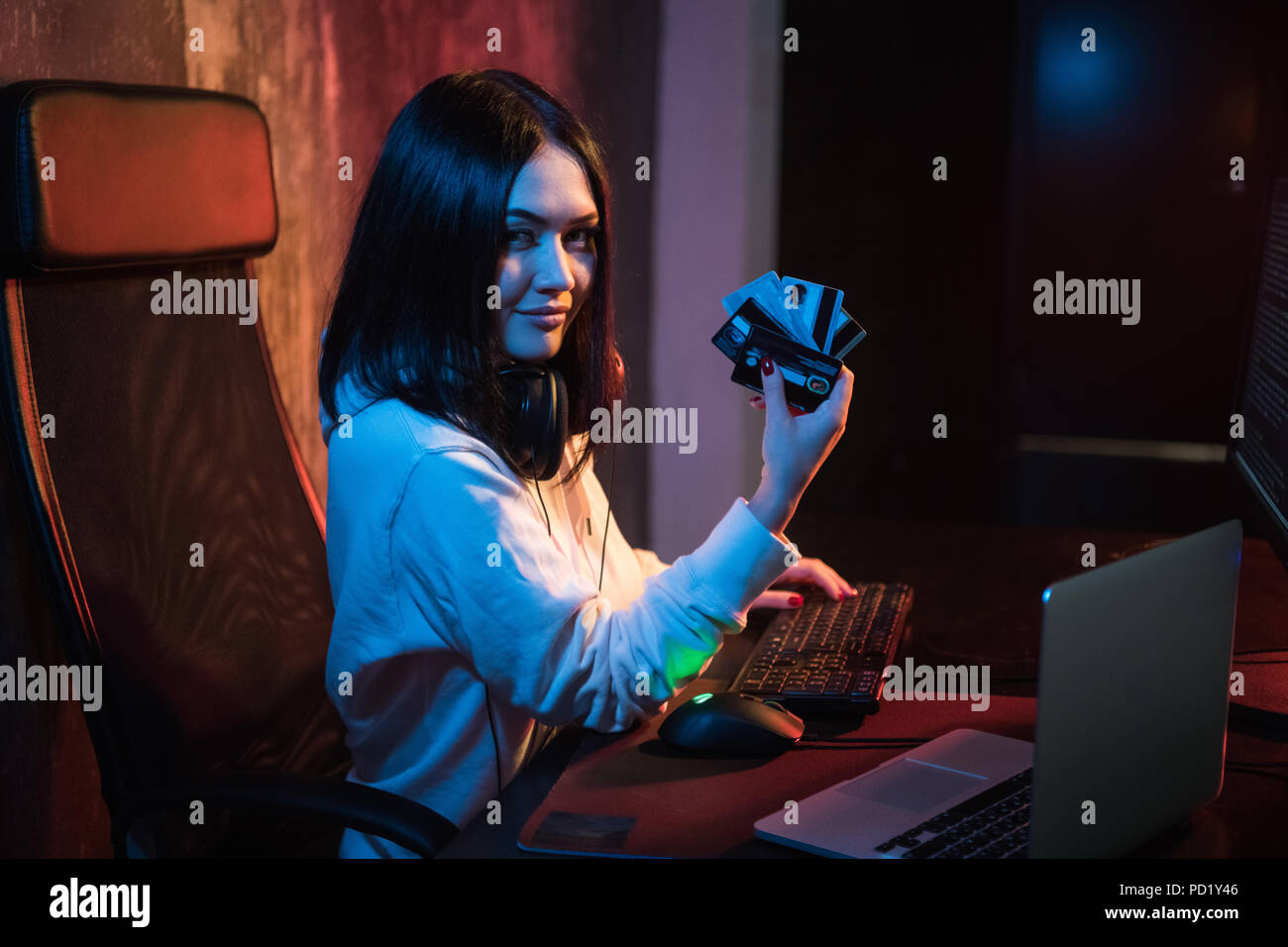 young teenager hacker girl in hoodie holding credit card violating private password holding credit card in cybercrime and cyber crime concept and internet information security concept Stock Photo