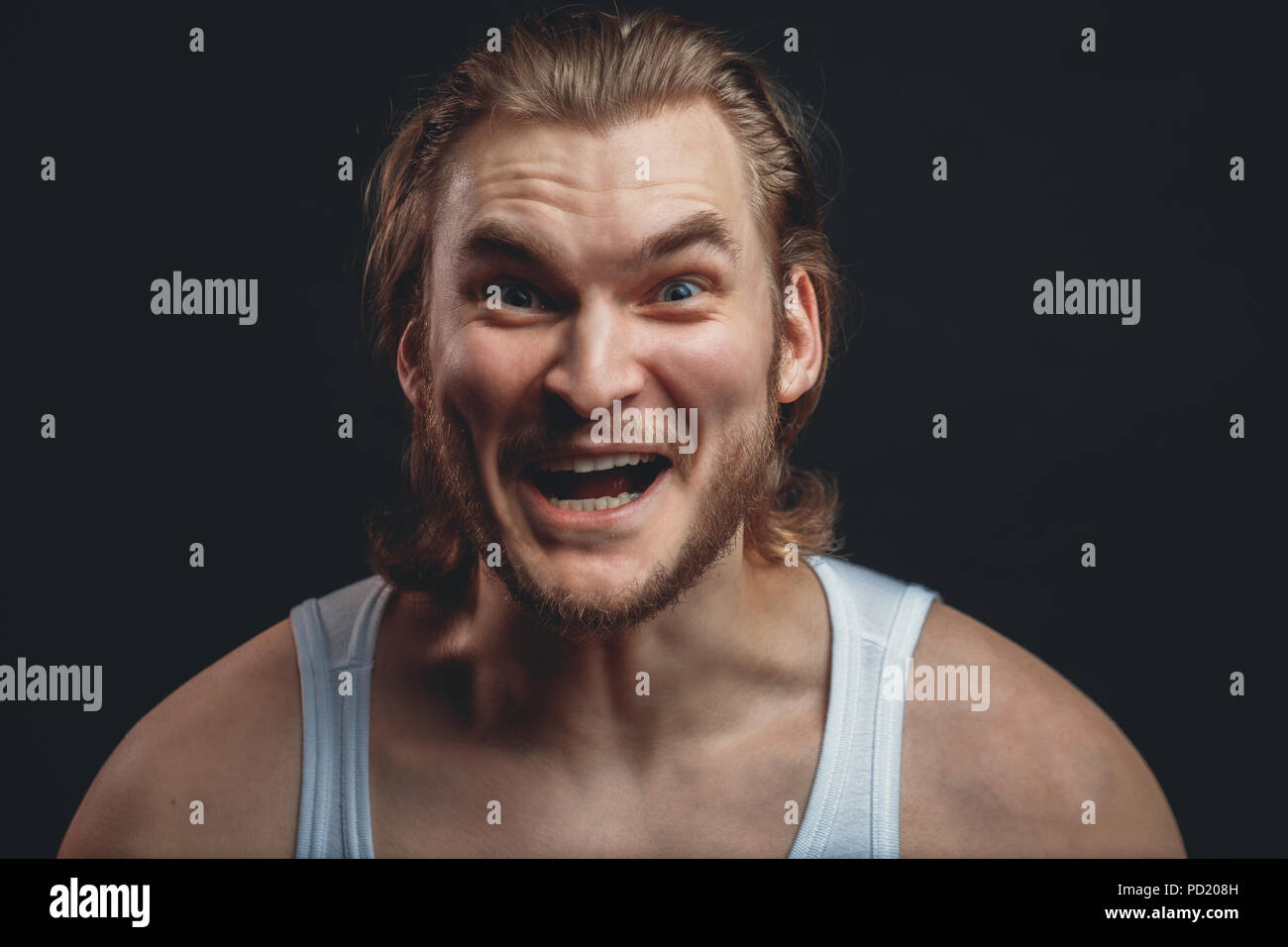 closeup portrait of strong guy with stupid face isolated black background. funny look. madness concept Stock Photo