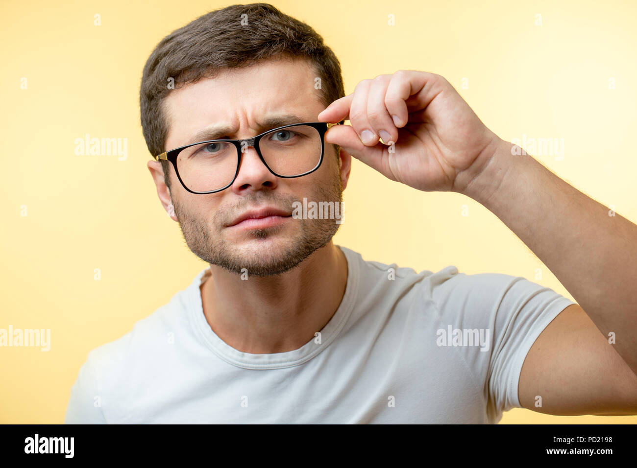 close up portrait of squinting man with glasses isolated on the yellow