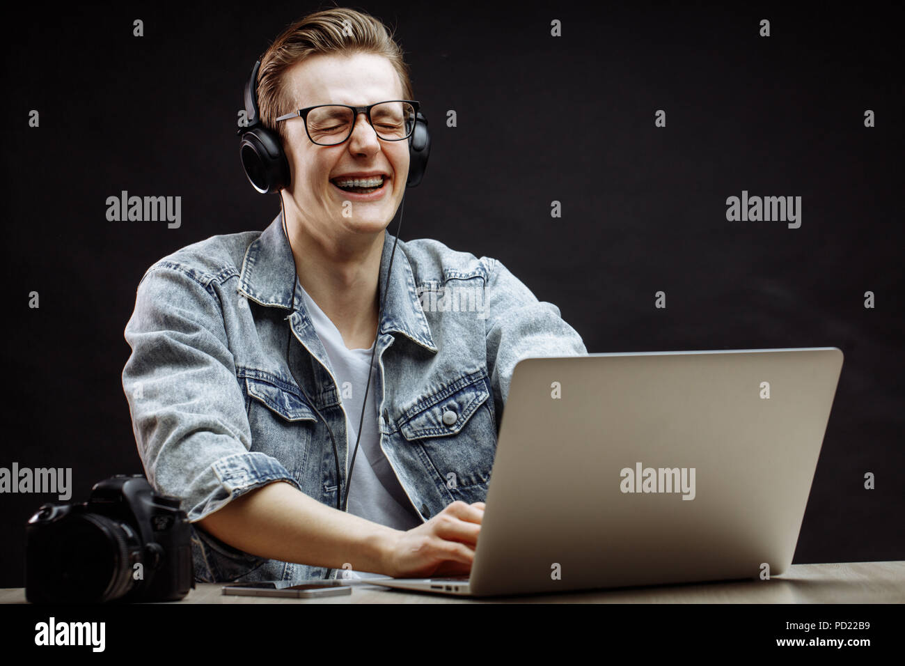 young male model is laughing with closed eyes while typing on the
