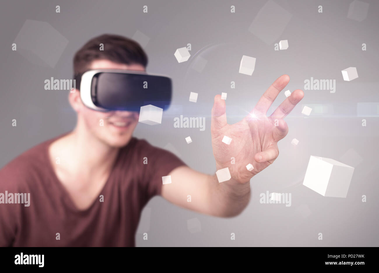 Young impressed man wearing virtual reality goggles with grey cubes ...