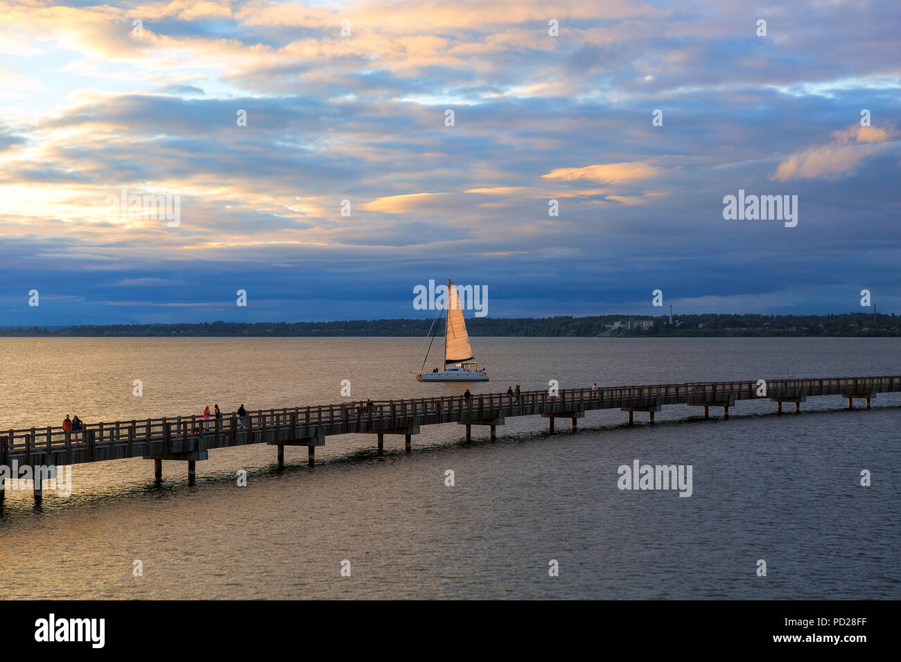 Sailing on Bellingham Bay by boardwalk at Boulevard Park in Bellingham Washington State during sunset Stock Photo