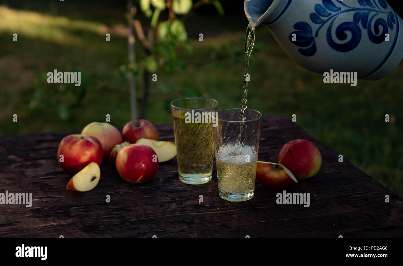 a man's hand pours Traditional apple wine in a refilled glass in the
