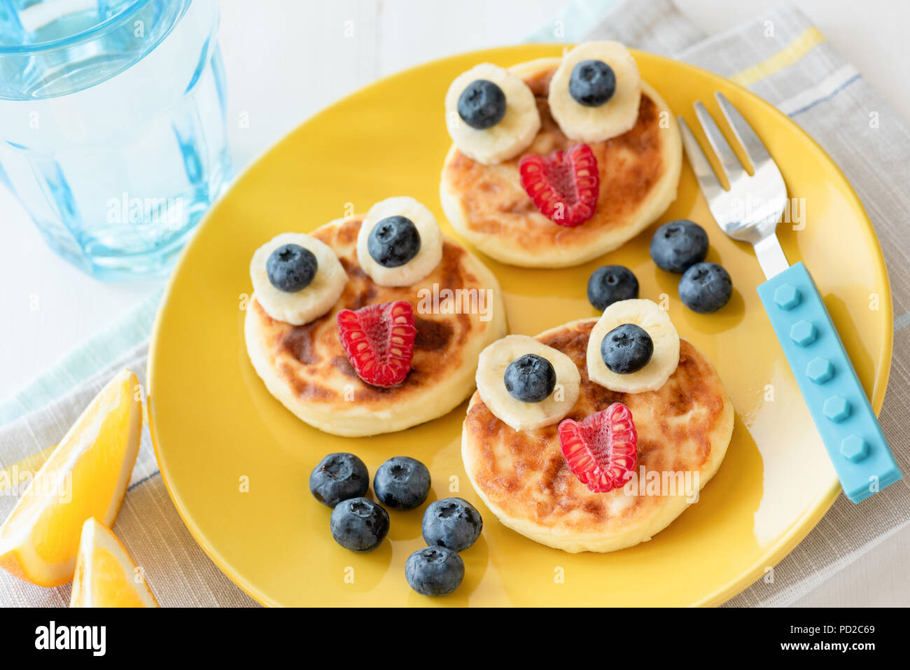 Fun food for kids. Pancakes with funny animal faces on colorful yellow plate. Kids meal. Selective focus Stock Photo