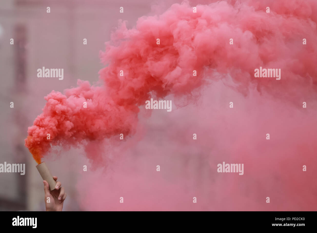 A man holding a hand flare with red smoke. Stock Photo