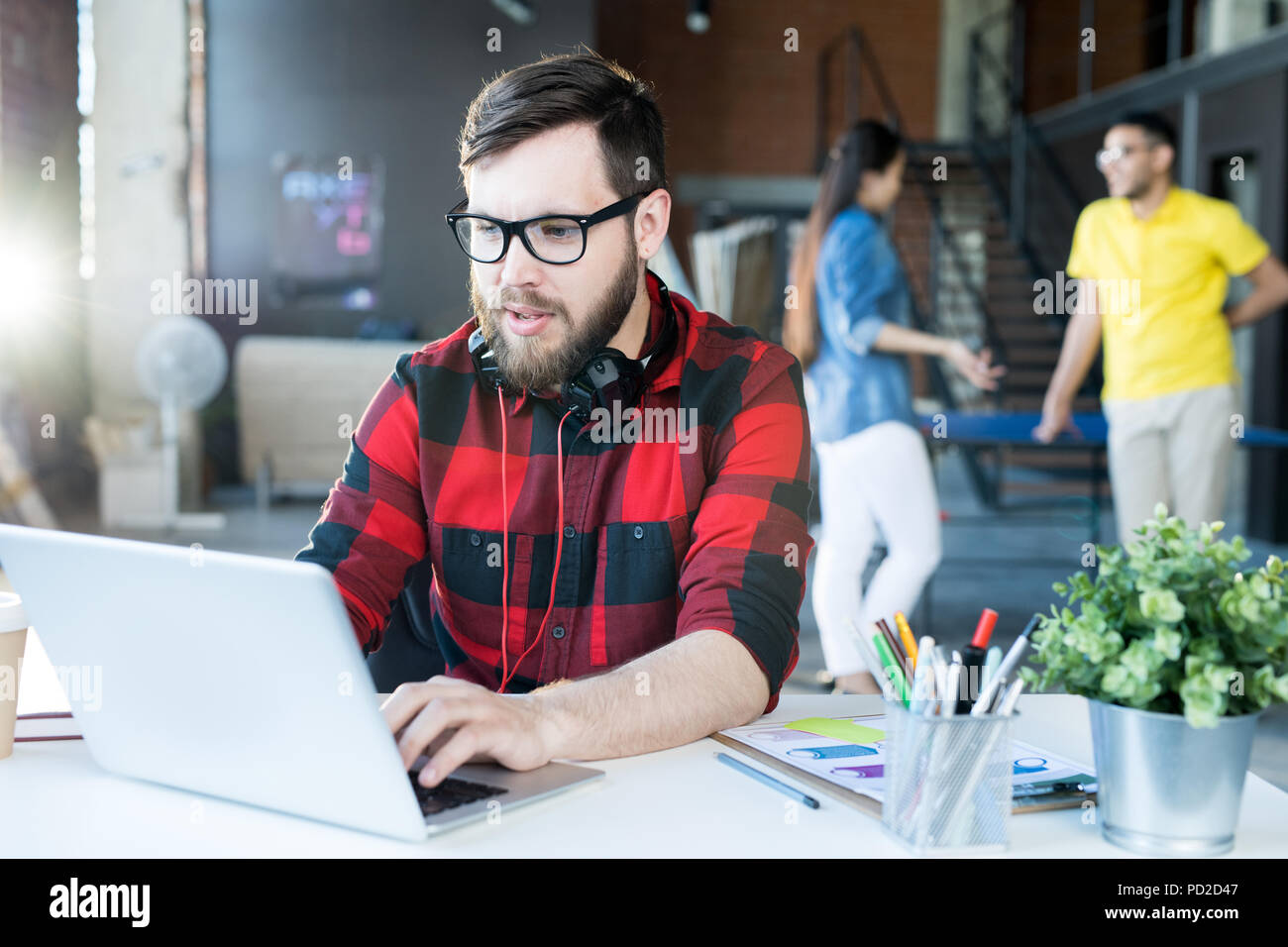 Modern Bearded Man Using Laptop in Coworking Space Stock Photo
