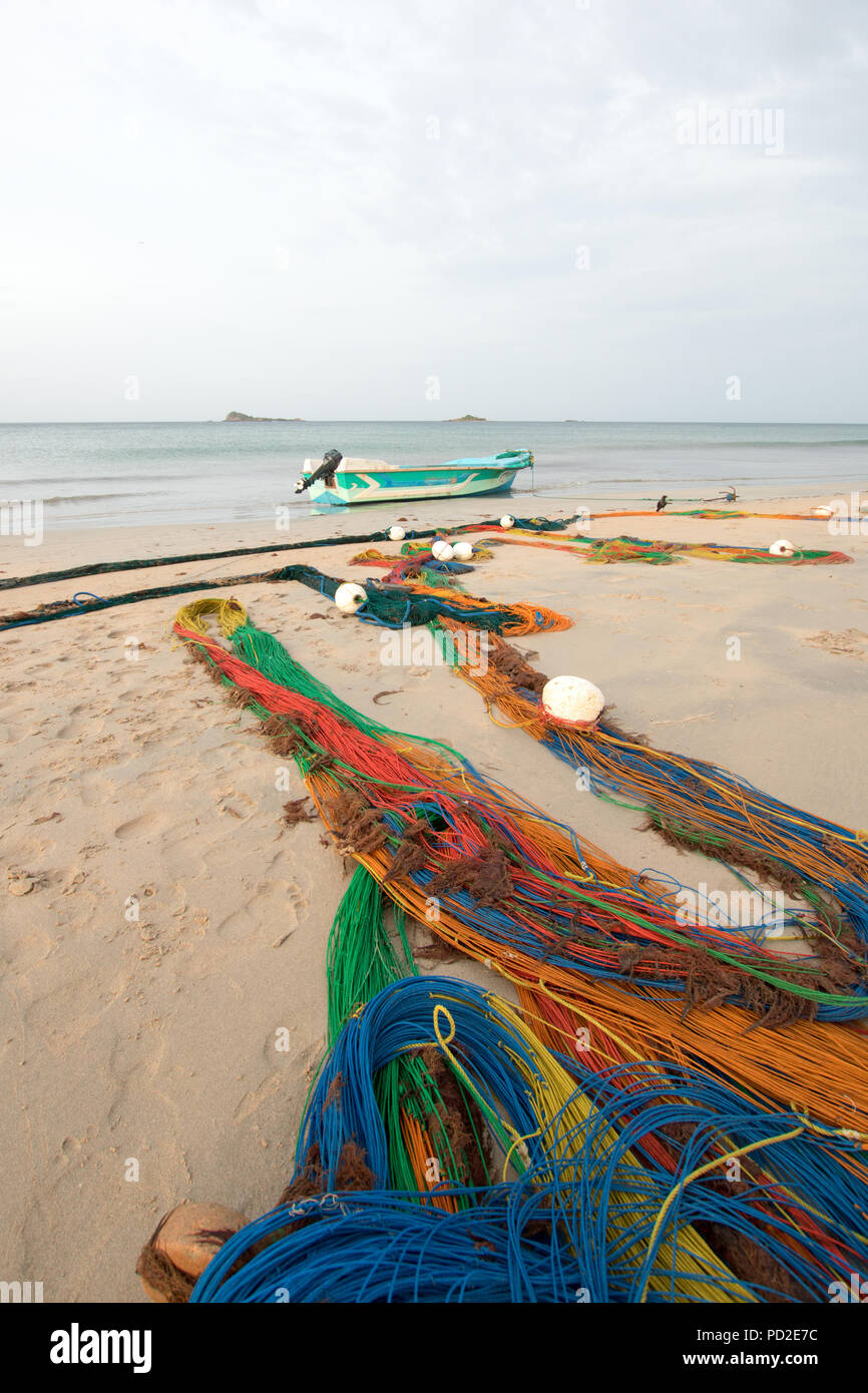 Small fishing boat next to fishing nets drying on Nilaveli beach in  Trincomalee Sri Lanka Asia Stock Photo - Alamy