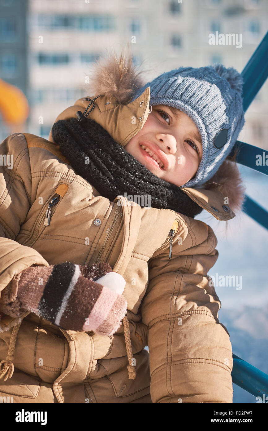 little boy in winter clothes walking on a children's colorful hill Stock Photo
