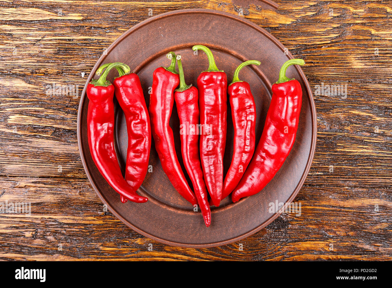 red pepper in a clay plate on dark wooden surface, top view Stock Photo ...