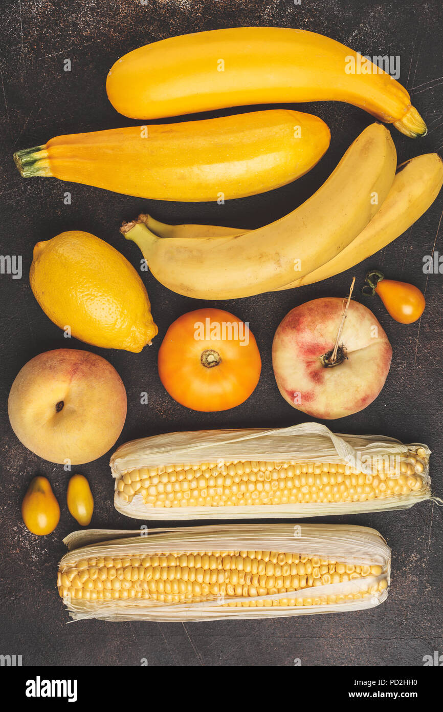 Assortment of yellow vegetables on a dark background, top view. Fruits and vegetables containing carotene. Stock Photo