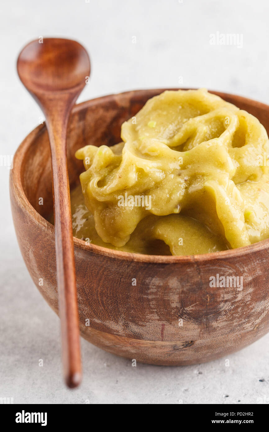 Green vegan banana avocado ice cream in a wooden bowl, top view, white