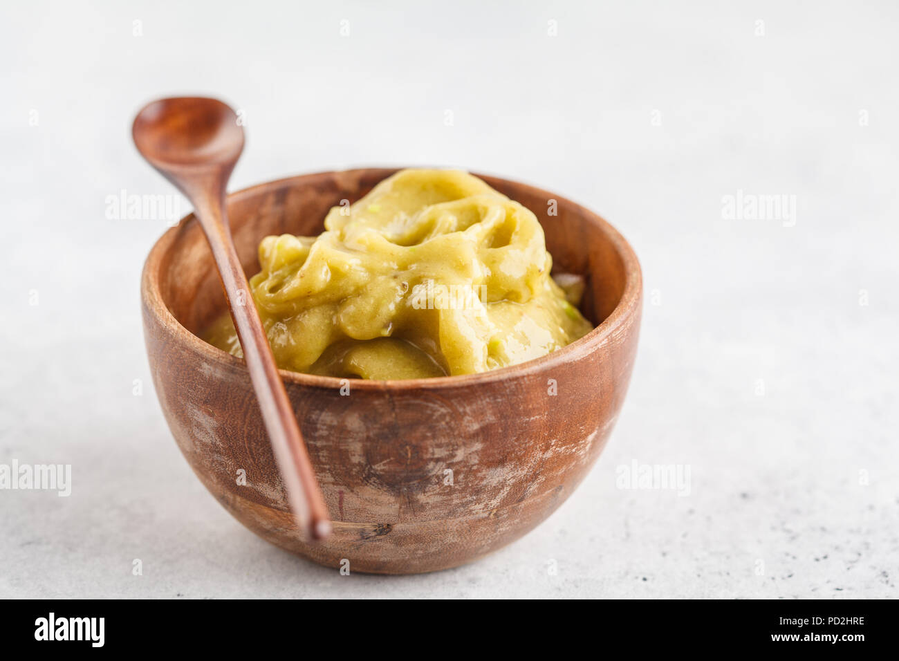 Green vegan banana avocado ice cream in a wooden bowl, top view, white