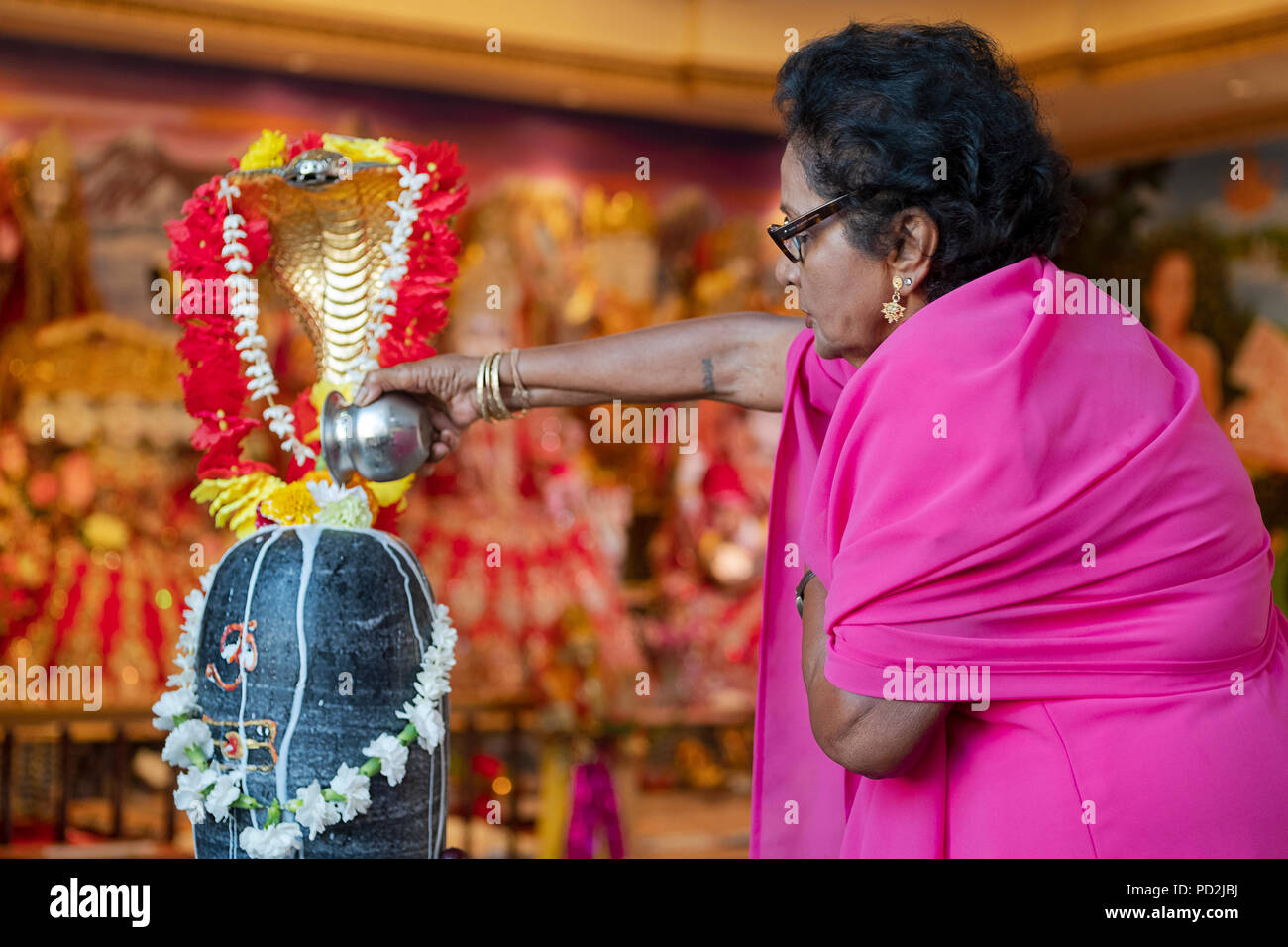 A woman pours milk of the statue of the deity Shiva at a Hindu tmeple