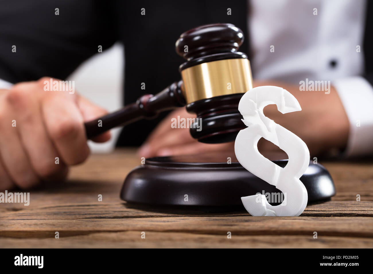 Close-up of a white paragraph symbol in front of judge striking gavel Stock Photo