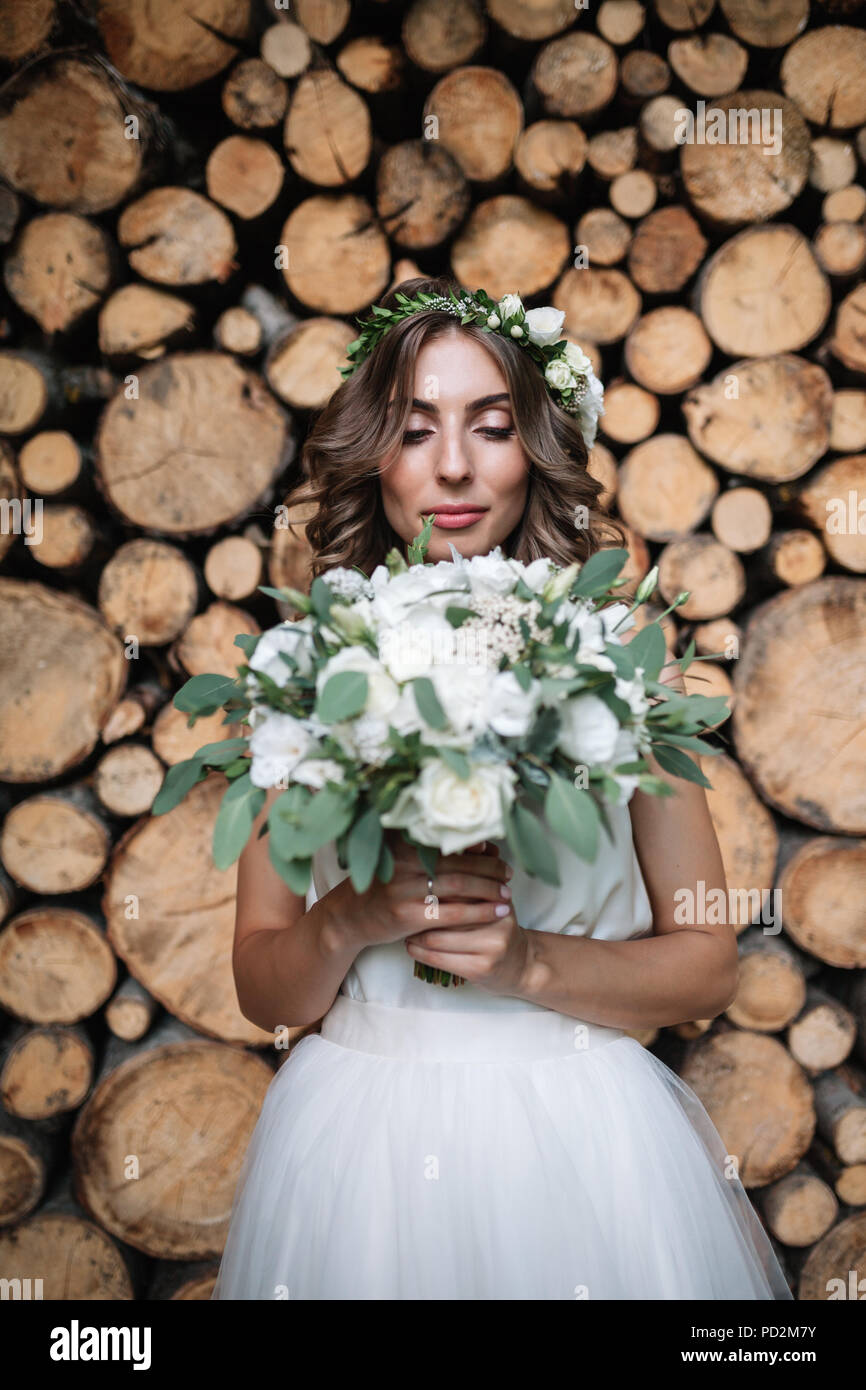Beautiful blonde happy bride in elegant white dress in a wreath with ...