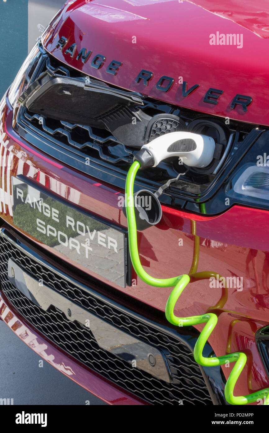 an electric powered range rover sport car on charge at a charger on the