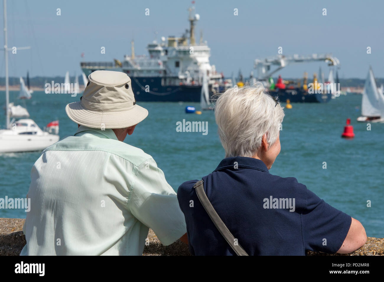 an elderly or older couple man and woman watching the yacht races and ...