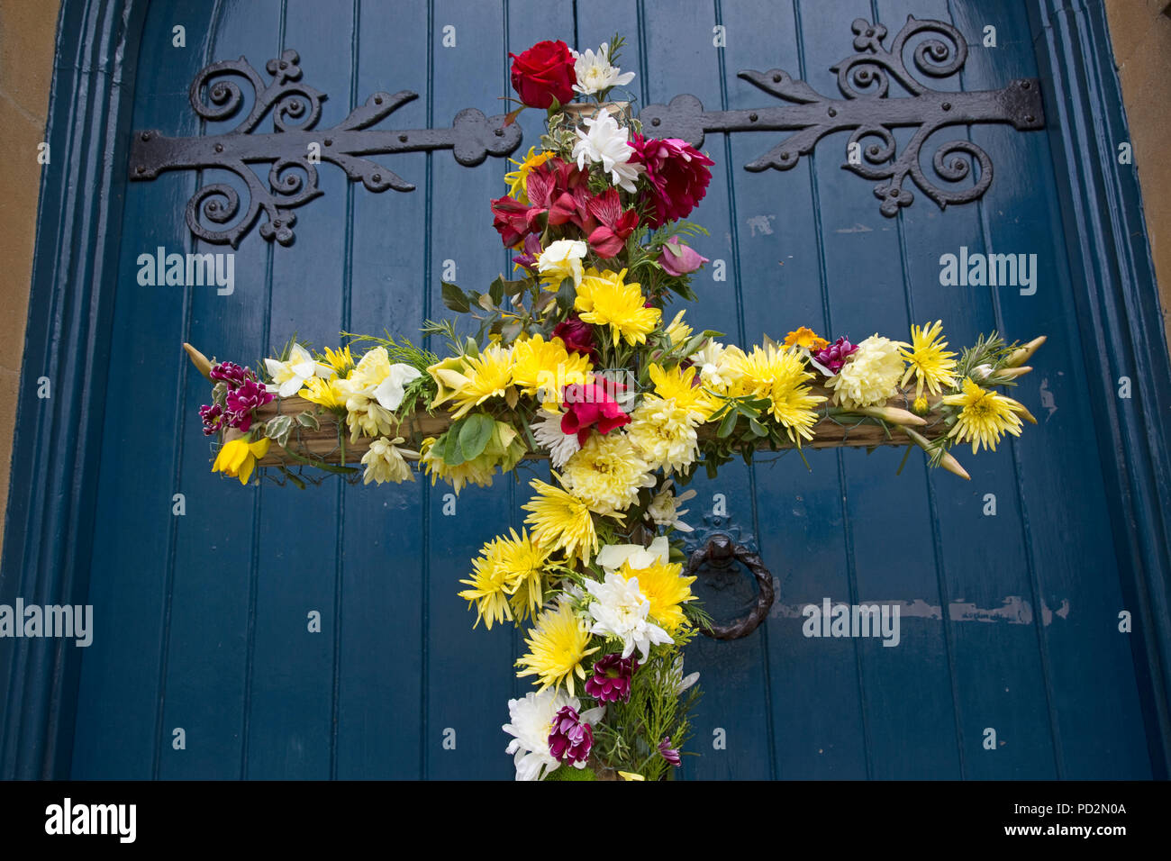 Closeup of Wooden Easter cross decorated with flowers outside church door Mickleton Methodist Church UK Stock Photo