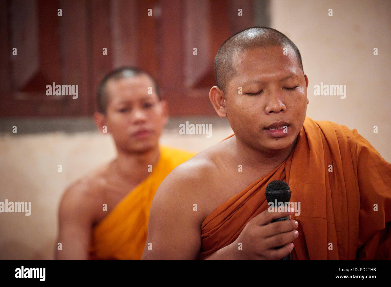 A Buddhist monk chanting with his eyes closed during a ceremony in one of the temples within their monastery. Stock Photo