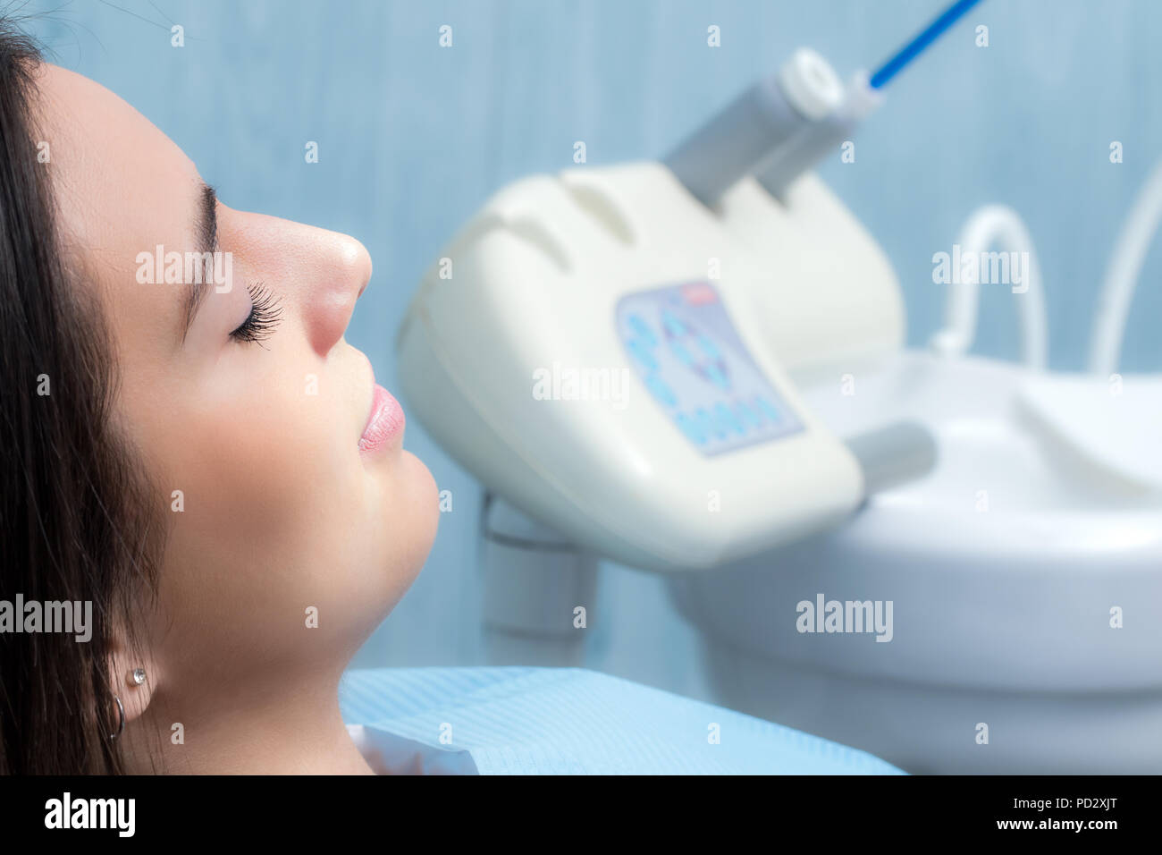 Close up side view portrait of young woman at dental check up.Girl laying with eyes closed with equipment in background. Stock Photo