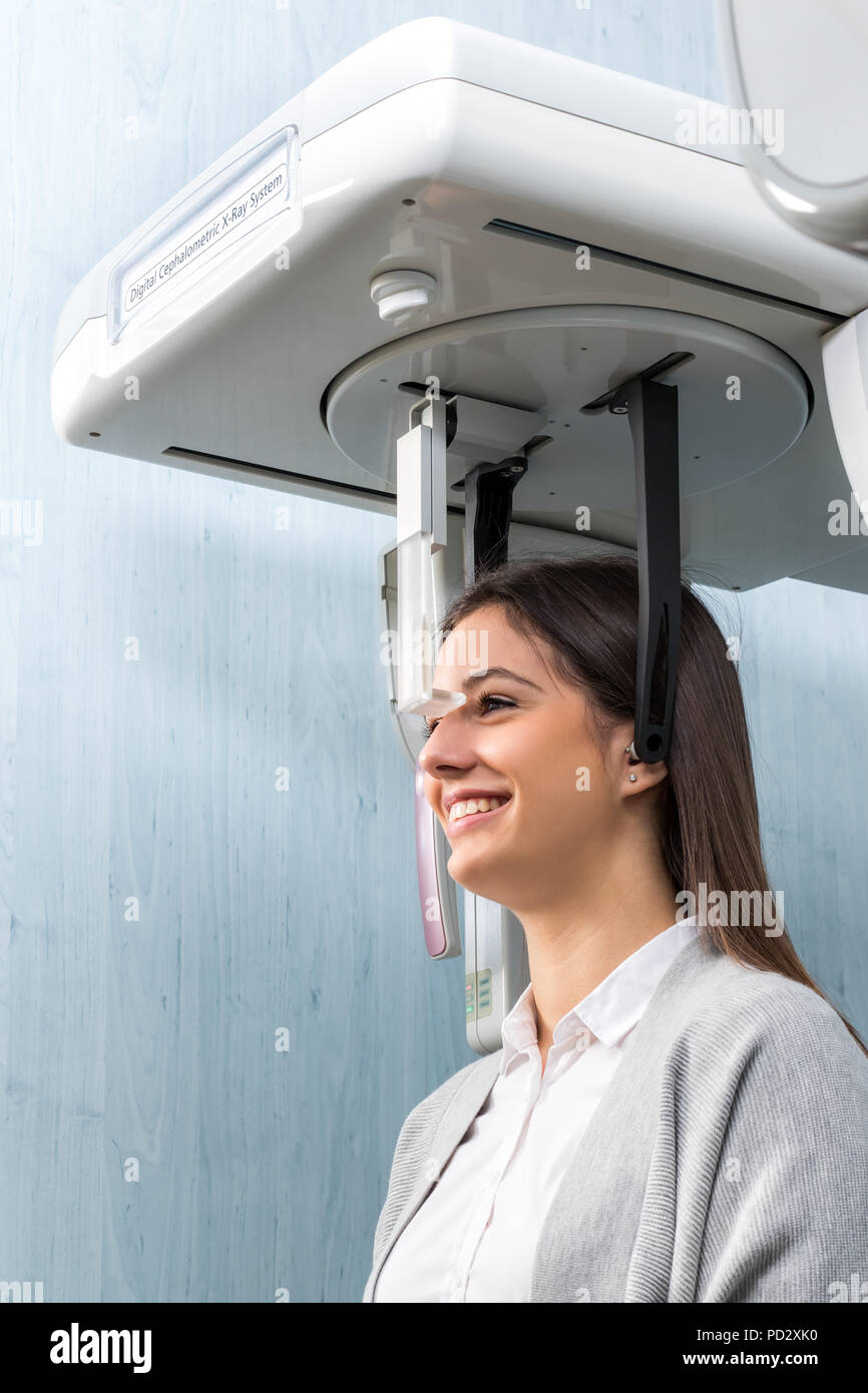 Close up side view portrait of woman taking dental examination with digital cephalometric x-ray machine in clinic. Stock Photo