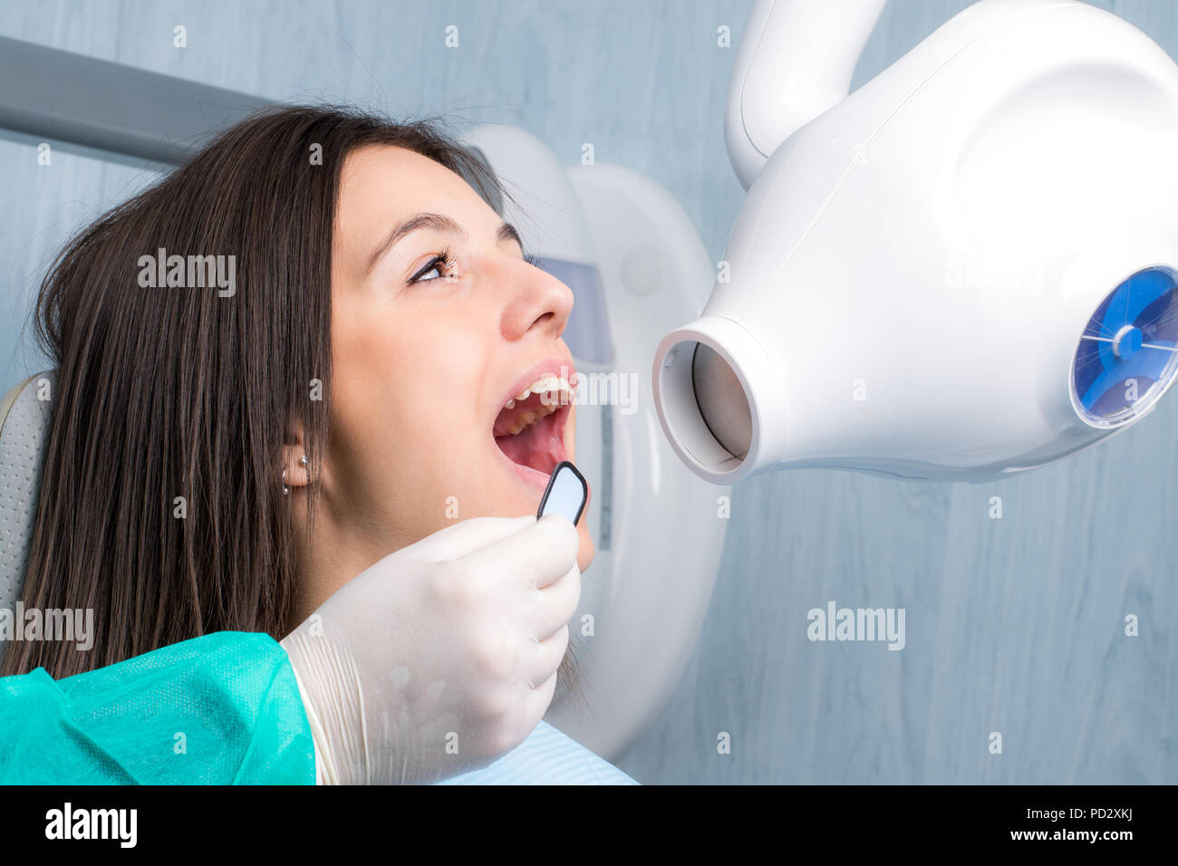 Close up portrait of young woman with open mouth next to x ray machine