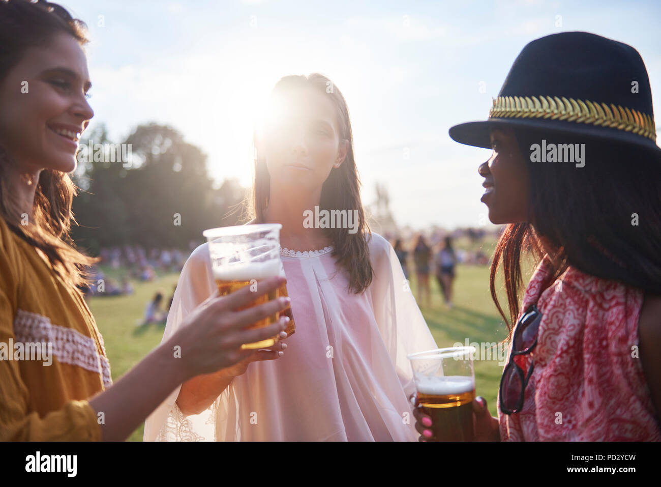 Three young female friends with glasses of beer at Holi Festival Stock Photo