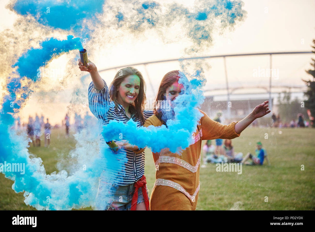 Two young women dancing with blue smoke bombs at Holi Festival Stock Photo