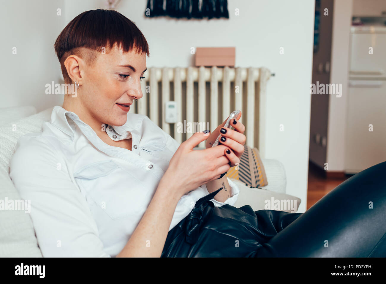 Woman sitting texting on mobile phone smiling Stock Photo