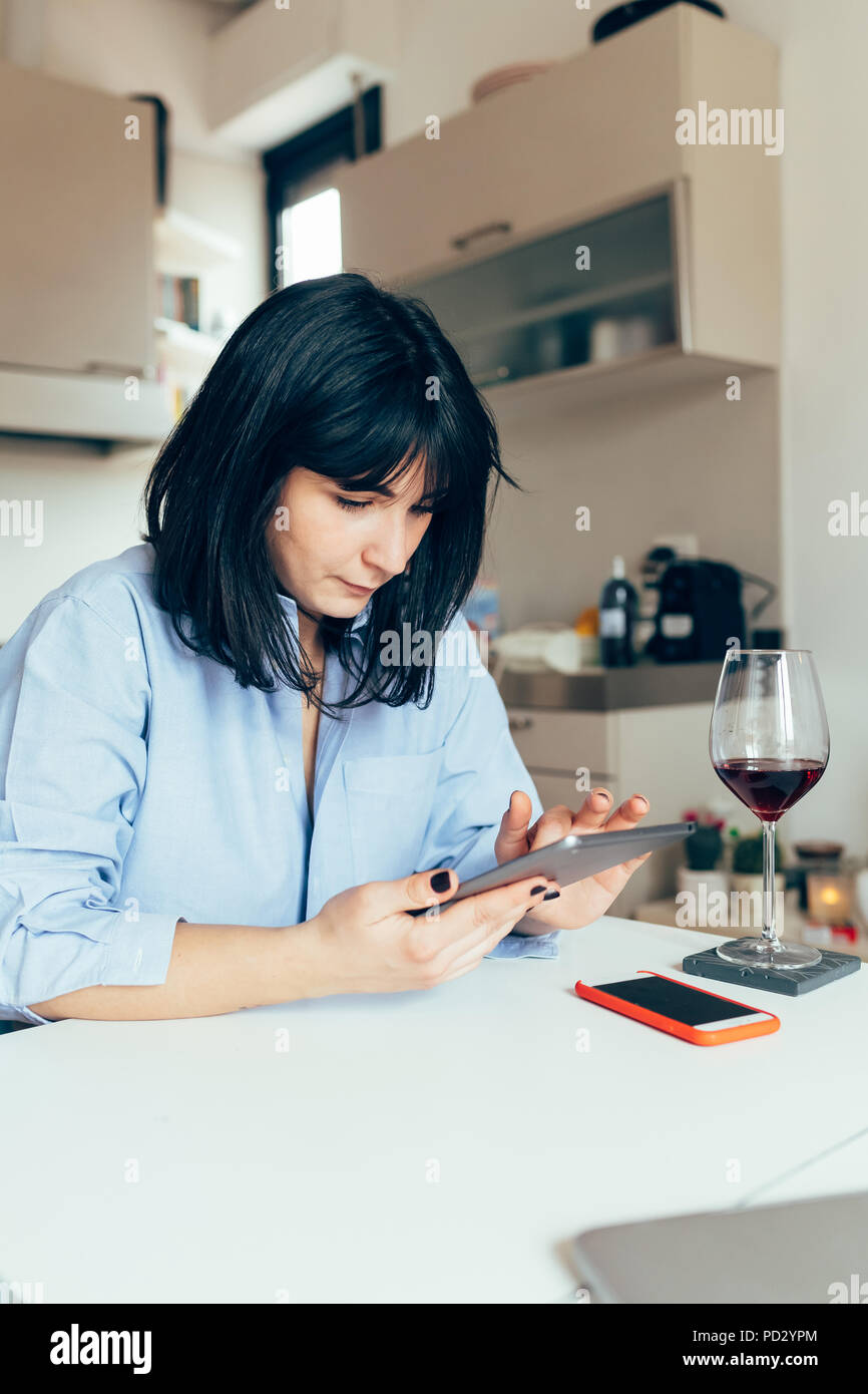 Woman sitting at table using digital tablet Stock Photo