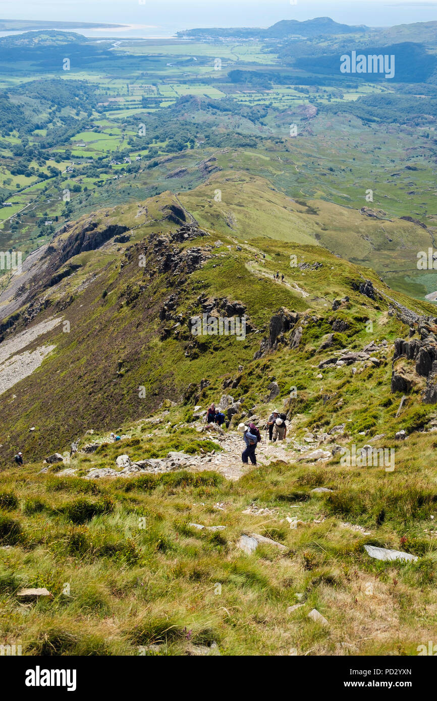 View down Cnicht mountain ridge to coast with hikers hiking up in Moelwyn hills of Snowdonia National Park. Croesor, Gwynedd, Wales, UK, Britain Stock Photo