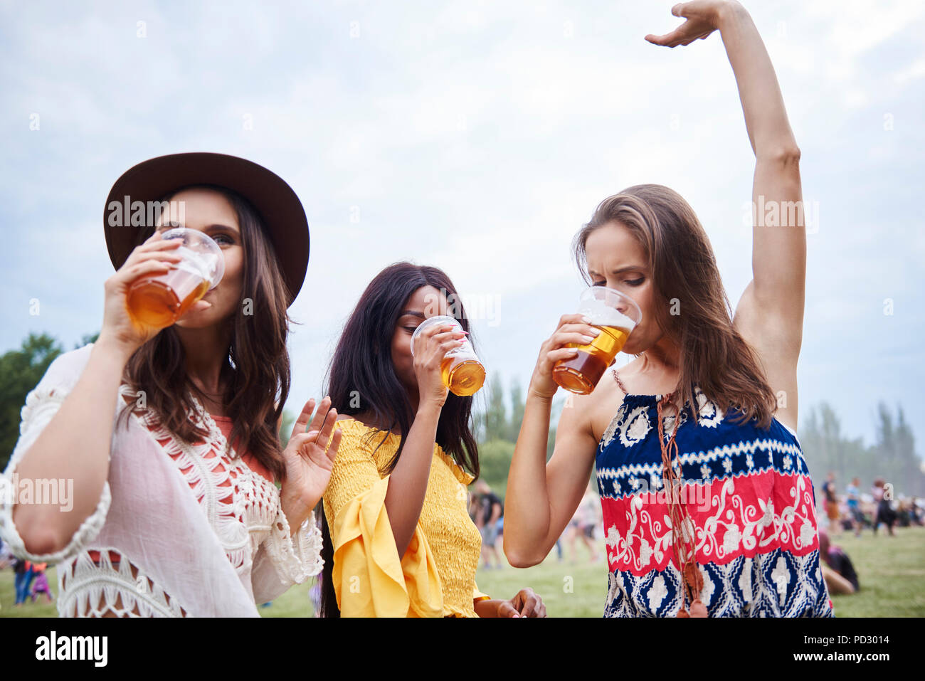 Friends drinking and dancing with arms raised in music festival Stock Photo