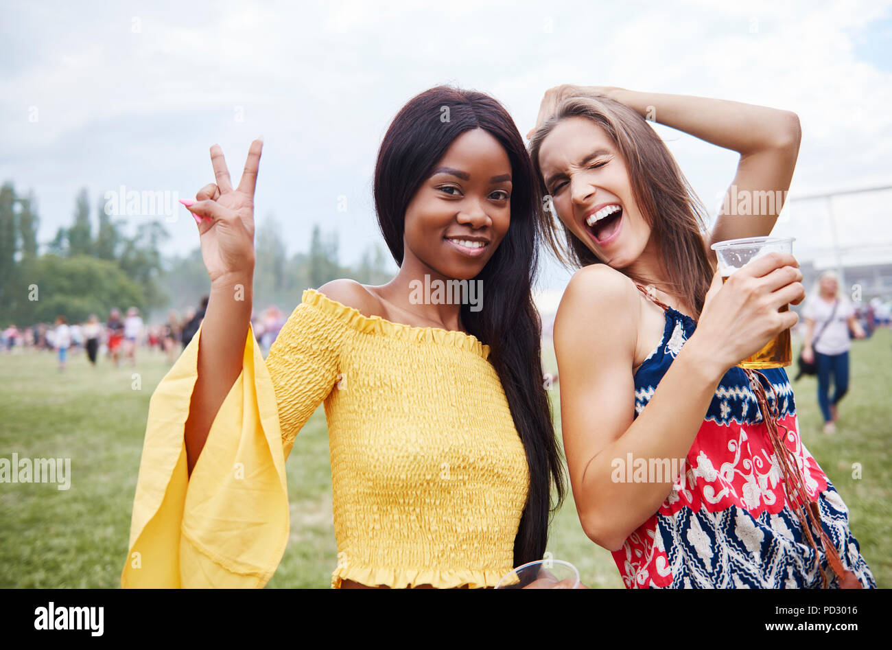 Friends drinking and dancing with arms raised in music festival Stock Photo