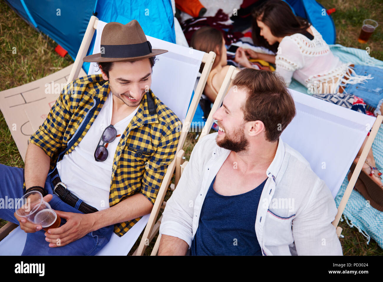 Friends sitting in deck chairs in music festival Stock Photo
