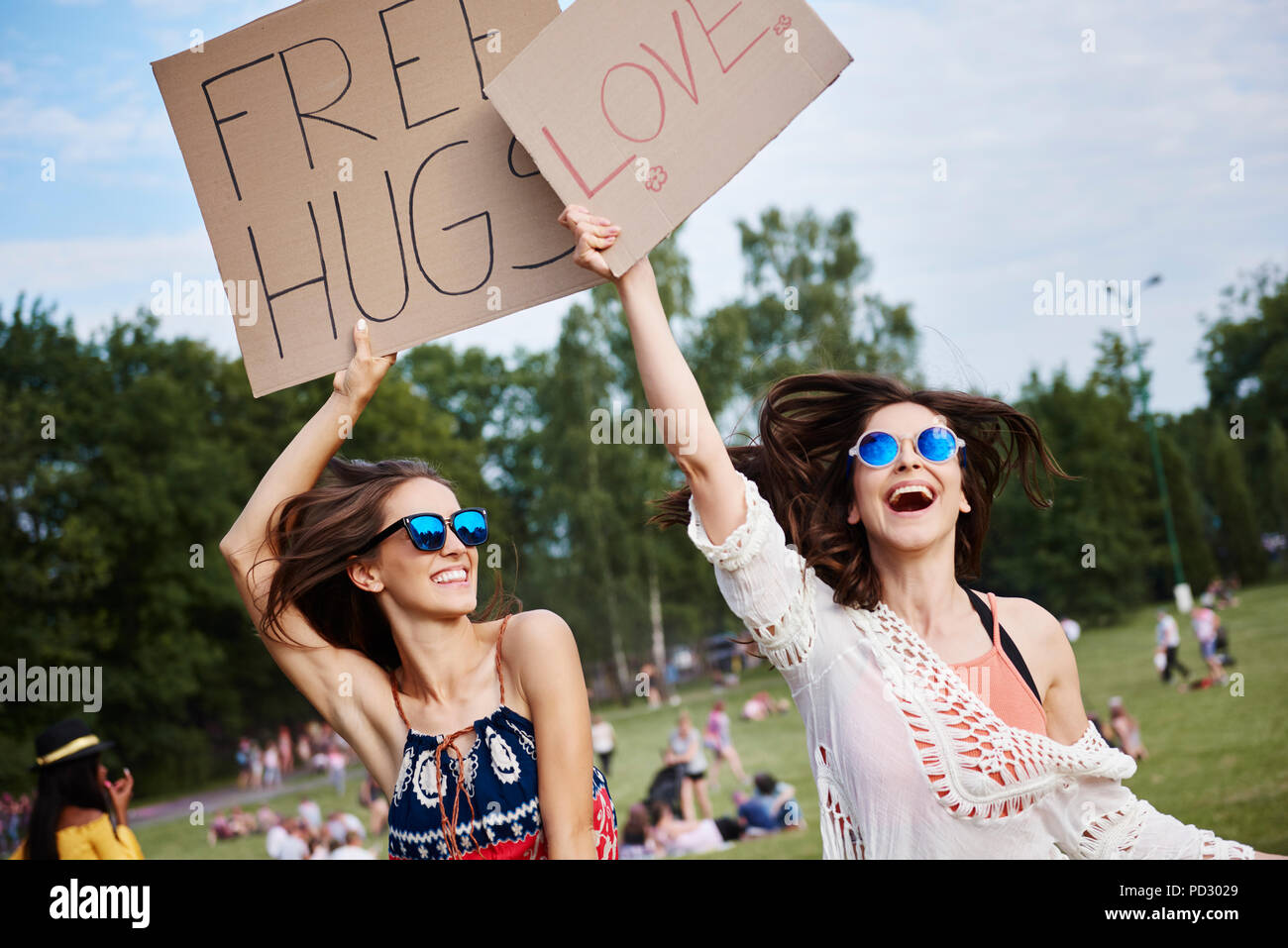 Friends holding up cardboard signs at music festival Stock Photo