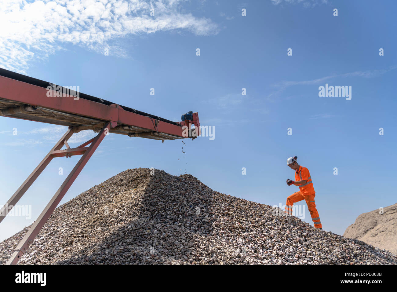 Worker checking handful of screened concrete in concrete recycling site Stock Photo