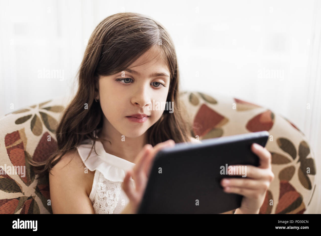 Girl using digital tablet on sofa Stock Photo