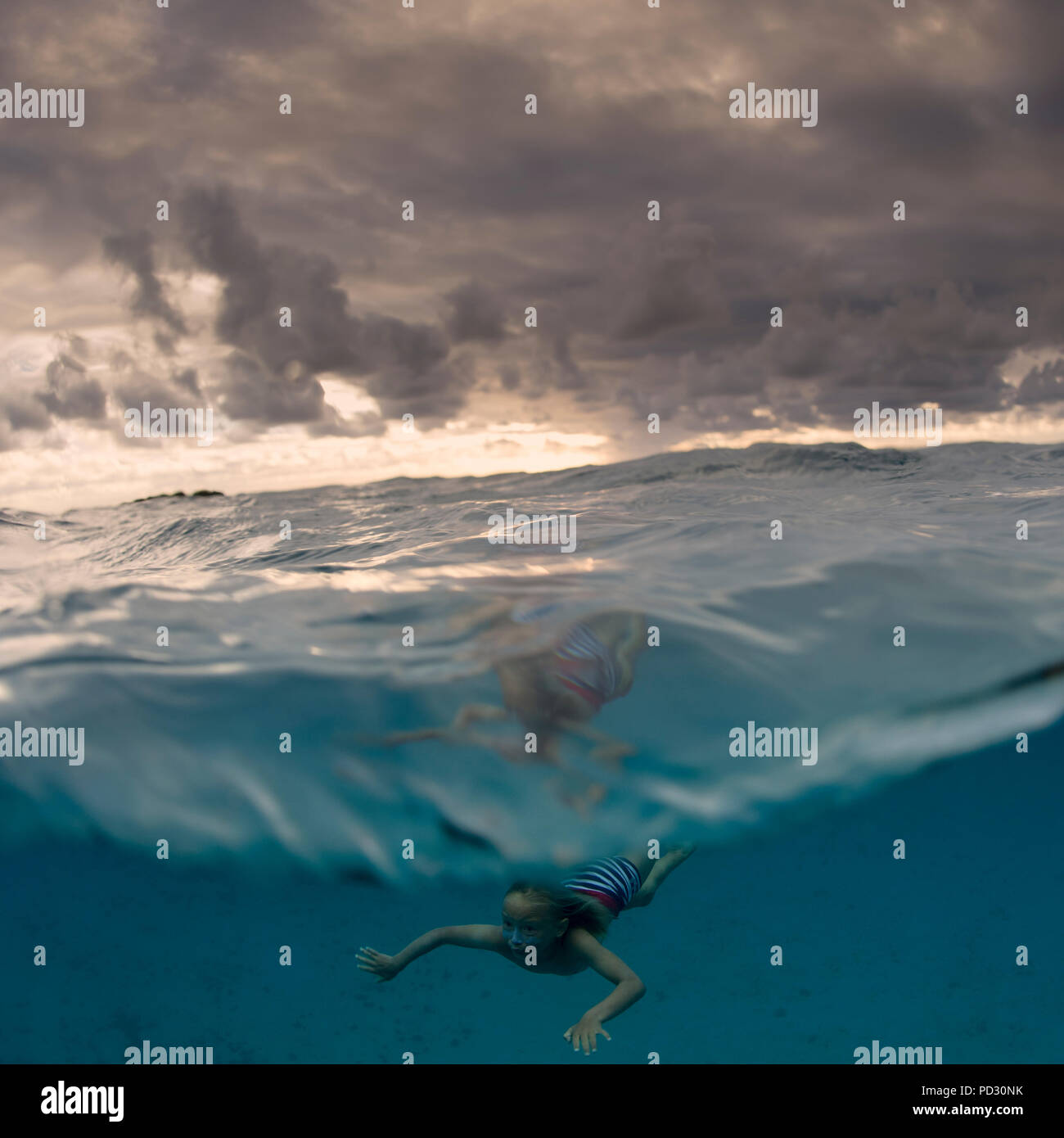 Young boy swimming underwater, split view, Tonga Stock Photo
